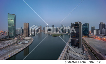 Cityscape of skyscrapers in Dubai Business Bay with water canal aerial night to day Cityscape of skyscrapers in Dubai Business Bay with water canal aerial night to day 98757343