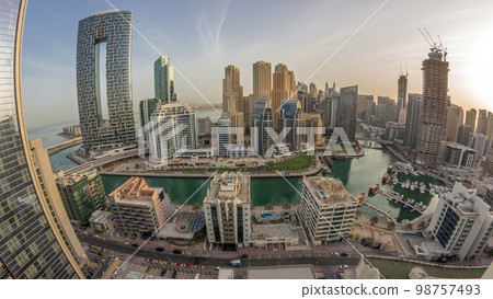 Dubai Marina with several boats and yachts parked in harbor and skyscrapers around canal aerial morning . Dubai Marina with several boats and yachts parked in harbor and skyscrapers around canal aerial morning . 98757493