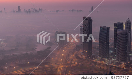 Big crossroad junction between JLT district and Dubai Marina intersected by Sheikh Zayed Road aerial night to day . 98757737