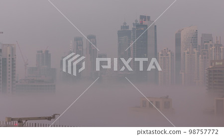 Dubai skyscrapers with morning fog in business bay district night to day . 98757772