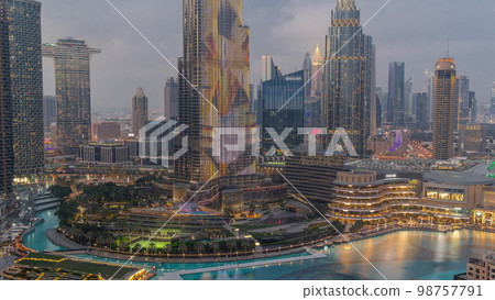 Skyscrapers rising above Dubai downtown day to night surrounded by modern buildings aerial top view Skyscrapers rising above Dubai downtown day to night surrounded by modern buildings aerial top view 98757791