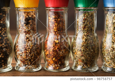 Glass mills with aromatic spices and herbs. Several grinders of different seasoning close up. Condiments for cooking. Glass mills with aromatic spices and herbs. Several grinders of different seasoning close up. Condiments for cooking. 98758757