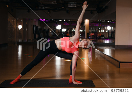 Young attractive smiling woman practicing yoga. Fit woman making cobra pose on yoga mat, exercising in studio. 98759231