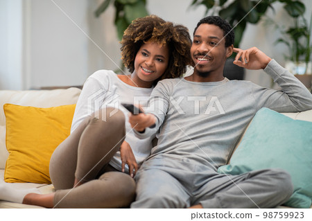 Happy african american affectionate couple watching TV together at home 98759923