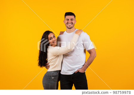 Glad cheerful young pretty arabic wife hugging tall husband, looking at camera, enjoy tender moment 98759978