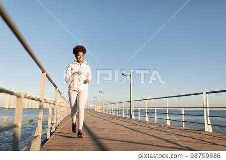 Outdoor Sports. Young Black Woman Jogging Outside On Wooden Pier Near Sea 98759986
