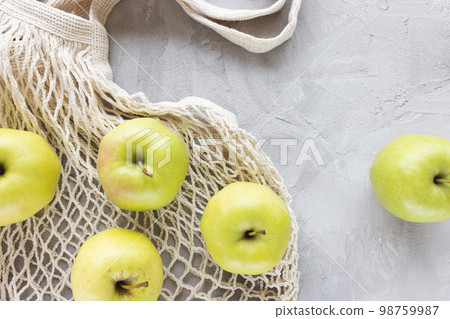 Reusable shopping mesh bag on gray with apples background. Healthy eating, fruits, zero waste, no plastic, eco friendly shopping, recycling concept. Flat lay, close up 98759987