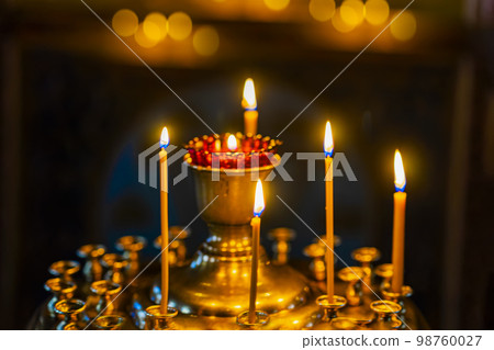 Lighted candles in gilded candlesticks and lamp in church. Blurred selective Focus 98760027