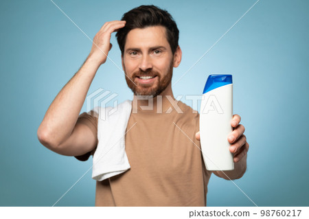 My choice. Handsome bearded man ready to take shower, standing with towel on shoulder, focus on bottle My choice. Handsome bearded man ready to take shower, standing with towel on shoulder, focus on bottle 98760217
