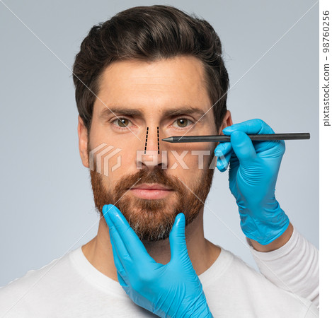Rhinoplasty concept. Handsome middle aged man with marking on his nose standing on grey background, closeup, cropped 98760256