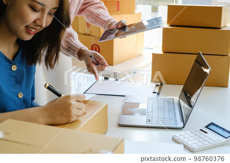 Asian small business owner working together with friend at home office. Business retail market and online sell marketing delivery, SME e-commerce concept. Asian small business owner working together with friend at home office. Business retail market and online sell marketing delivery, SME e-commerce concept. 98760376