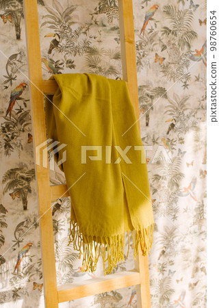 A mustard scarf hangs on a wooden staircase 98760654