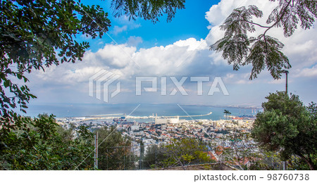 Port with a long protective spit (artificial) Huge cranes on the right side of the ship in the sea, a larger tall building in the port in Haifa 98760738