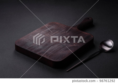 Empty metal spoon on dark textured concrete background 98761292