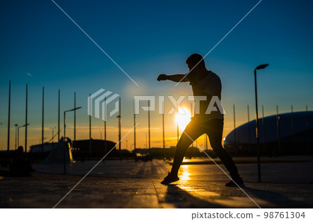 A man trains boxing at sunset outdoors. 98761304