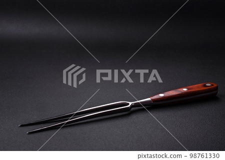 Metal kitchen fork on a dark textured concrete background 98761330