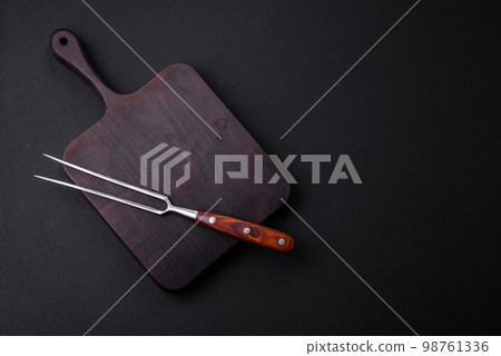 Metal kitchen fork on a dark textured concrete background 98761336