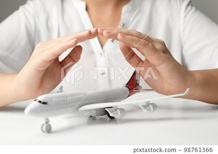 Woman covering toy plane at white table, closeup. Logistics and wholesale concept 98761366
