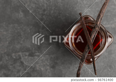 Aromatic homemade vanilla extract on grey table, top view. Space for text 98761400