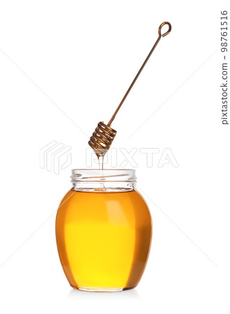 Honey dripping from dipper into jar isolated on white Honey dripping from dipper into jar isolated on white 98761516