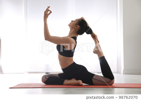 Woman practicing one legged king pigeon asana in yoga studio. Eka pada rajakapotasana pose Woman practicing one legged king pigeon asana in yoga studio. Eka pada rajakapotasana pose 98762070