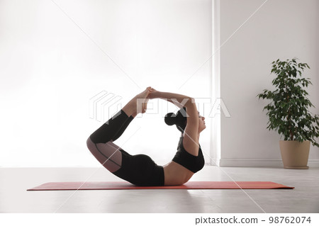 Woman practicing bow asana in yoga studio. Dhanurasana pose Woman practicing bow asana in yoga studio. Dhanurasana pose 98762074
