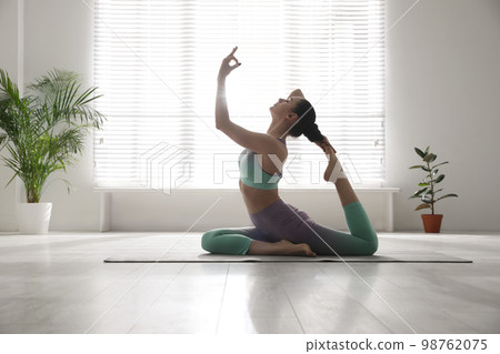 Woman practicing one legged king pigeon asana in yoga studio. Eka pada rajakapotasana pose Woman practicing one legged king pigeon asana in yoga studio. Eka pada rajakapotasana pose 98762075