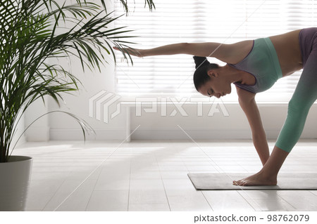 Young woman practicing extended triangle asana in yoga studio. Utthita Trikonasana pose 98762079