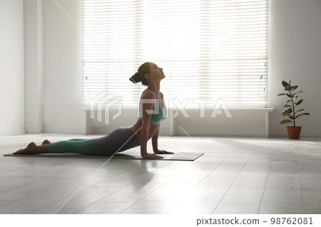 Woman practicing cobra asana in yoga studio. Bhujangasana pose Woman practicing cobra asana in yoga studio. Bhujangasana pose 98762081