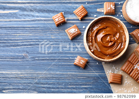 Salted caramel on blue wooden table, flat lay. Space for text 98762099