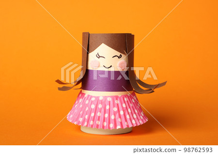 Toy doll made of toilet paper hub on orange background 98762593