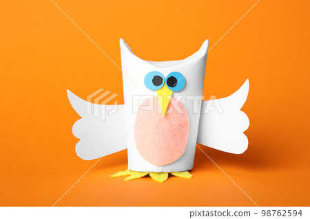 Toy owl made of toilet paper hub on orange background Toy owl made of toilet paper hub on orange background 98762594