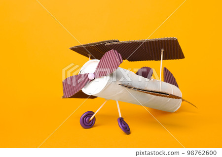 Toy plane made of toilet paper hub on yellow background 98762600