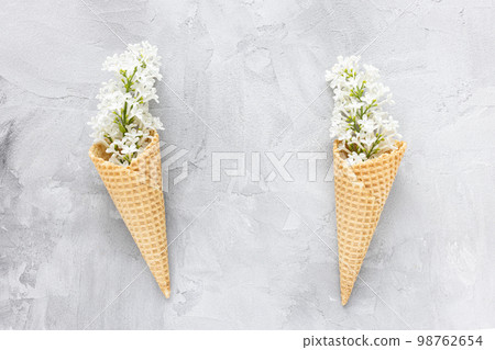Fresh white lilac flowers in waffle ice cream cone on gray background. Flat lay, top view, copy space, spring abstract floral background. 98762654