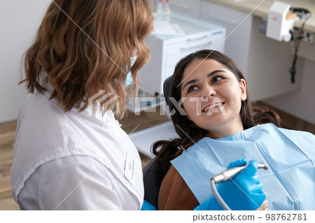 Dentist drilling tooth of female patient in dental chair Dentist drilling tooth of female patient in dental chair 98762781