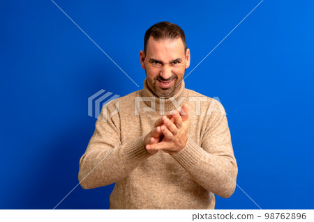 Close-up portrait of cunning, evil, cunning and scheming man, man trying to plot, plan something, screw up, hurt someone, isolated on blue background. Negative human emotions, facial expressions. Close-up portrait of cunning, evil, cunning and scheming man, man trying to plot, plan something, screw up, hurt someone, isolated on blue background. Negative human emotions, facial expressions. 98762896