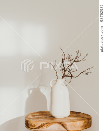 Modern minimalist style interior with ceramic vase with branch on wood table 98762982