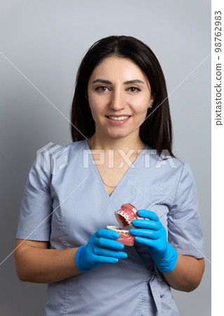 Doctor orthodontist showing model of human jaw with wire braces attached 98762983