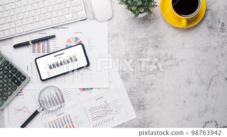 Smart phone with charts and reports on office desk workplace. Top view flat lay 98763942