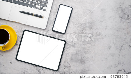 Office desk workplace with blank screen tablet and smart phone, laptop, pen and cup of coffee, Top view flat lay with copy space. Office desk workplace with blank screen tablet and smart phone, laptop, pen and cup of coffee, Top view flat lay with copy space. 98763943