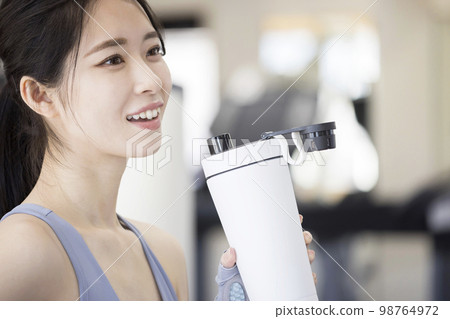 在健身房訓練後喝蛋白質的年輕女性 98764972