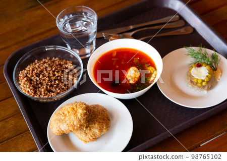 Plates with soup, buckwheat porridge, cutlets and salad on tray. Russian traditional dishes Plates with soup, buckwheat porridge, cutlets and salad on tray. Russian traditional dishes 98765102