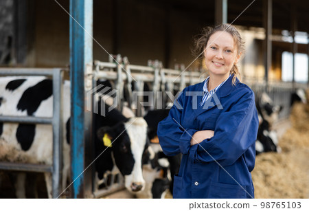 Positive woman farmer in cowshed 98765103