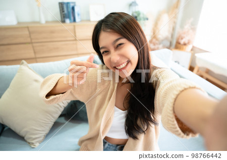 Pretty young asian female with big smile sitting at living room 98766442