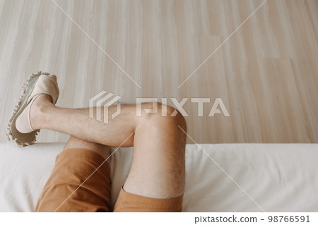 Top view of man sitting on sofa with crossing legs in cozy loft room. Top view of man sitting on sofa with crossing legs in cozy loft room. 98766591