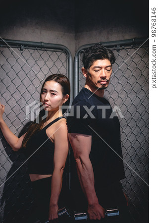 在鐵絲網前擺姿勢的男人和女人 在鐵絲網前擺姿勢的男人和女人 98768146