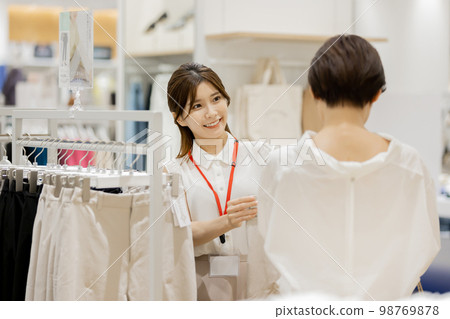 Apparel clerk recommending new clothes Apparel clerk recommending new clothes 98769878
