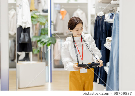 Apparel store clerk managing inventory Apparel store clerk managing inventory 98769887