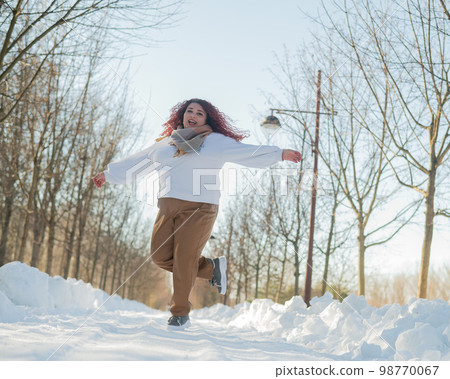 Smiling chubby redhead woman running in park in winter. Smiling chubby redhead woman running in park in winter. 98770067