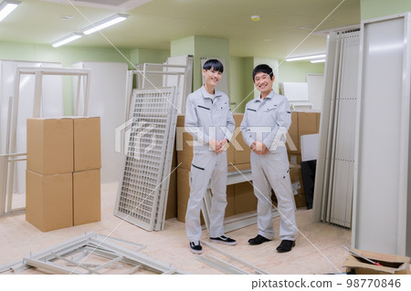 Portrait of two young men in work clothes standing indoors in an apartment building under construction Portrait of two young men in work clothes standing indoors in an apartment building under construction 98770846